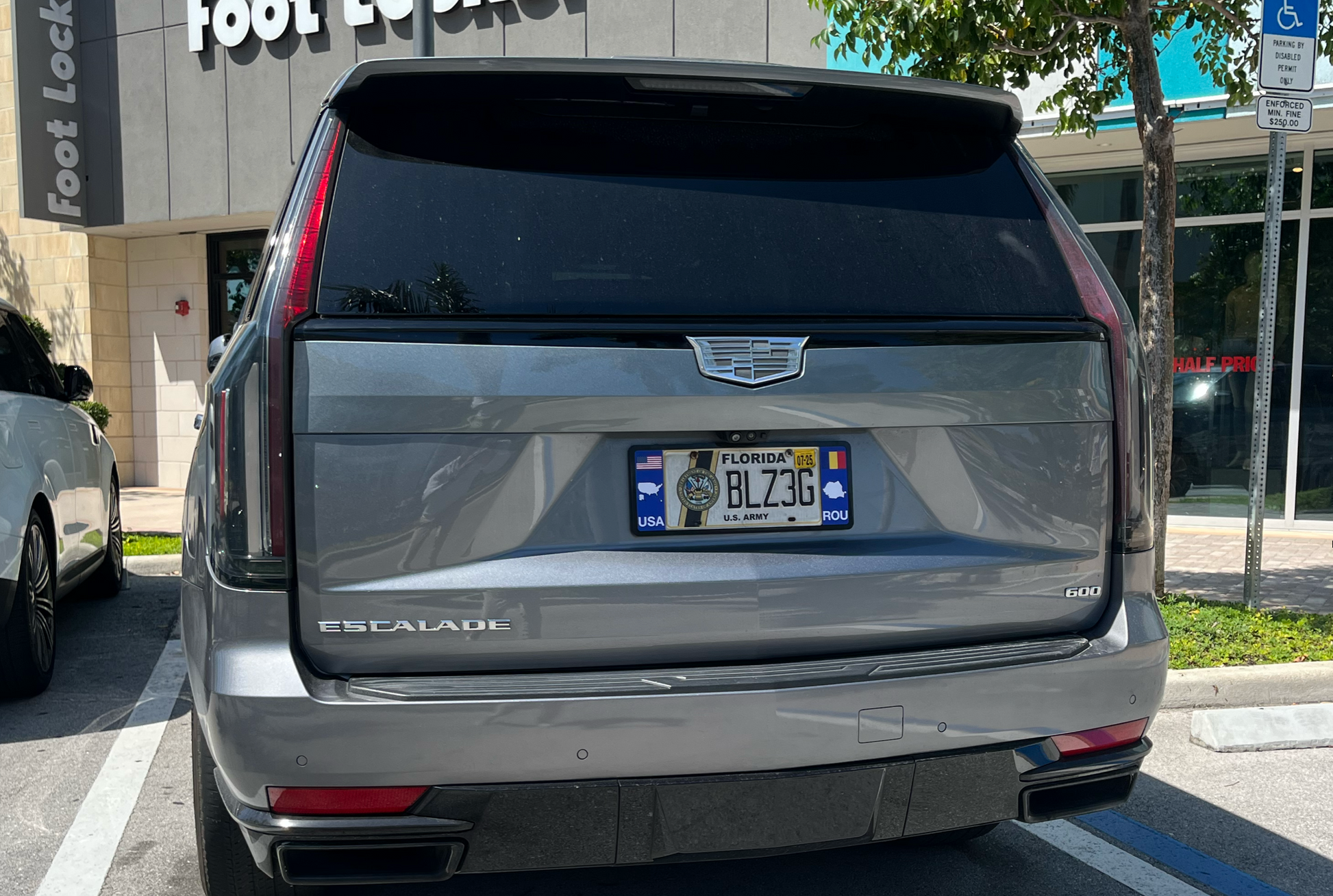 Back view of a Cadillac Escalade with DFS Romania ROU license plate frame in an urban setting.