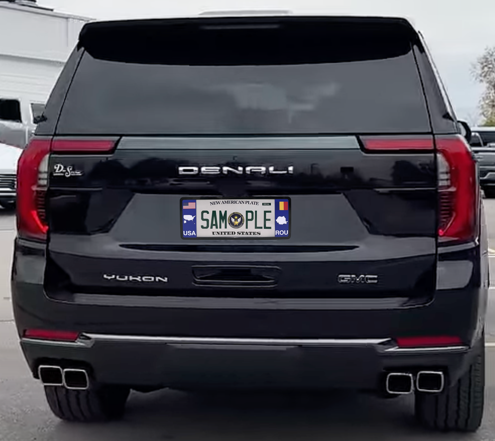 A black elongated Romania license plate frame mounted on a silver GMC Yukon AT4 SUV by DFS Brands.
